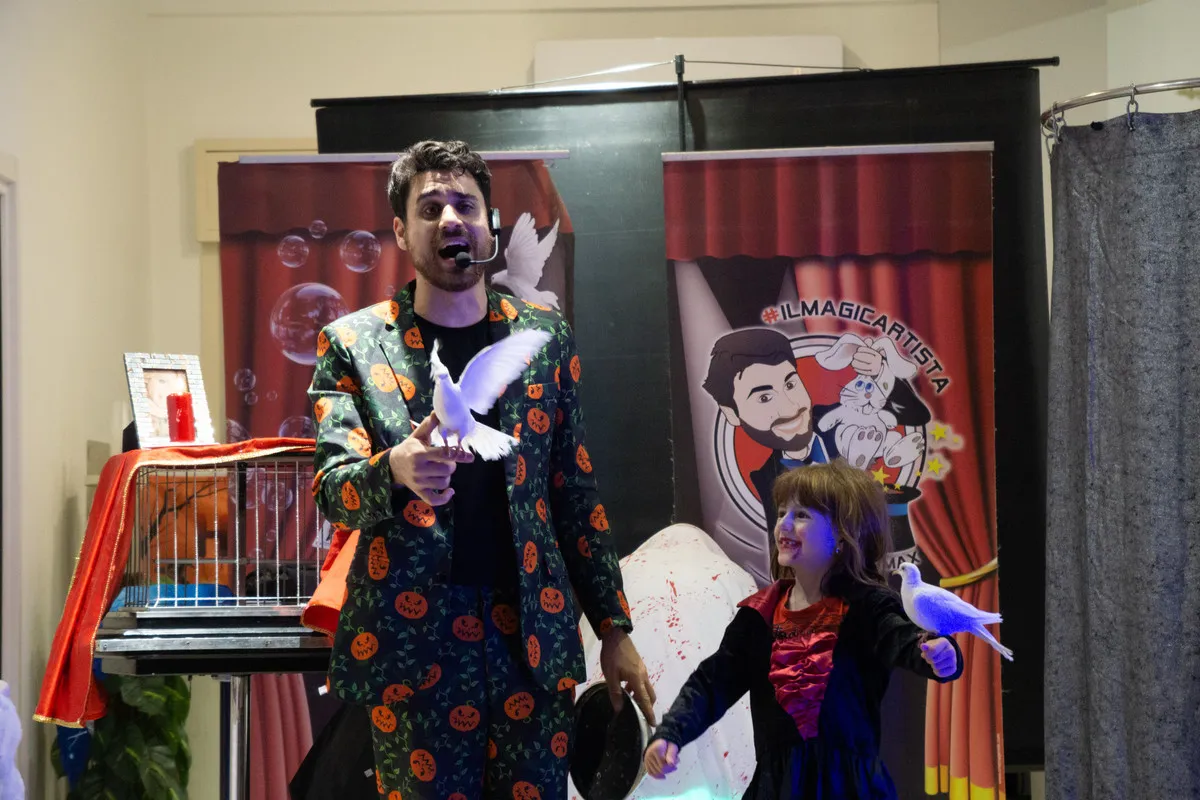 Una colomba bianca appare tra le mani del Mago Max accanto alla bambina chiamata sul palco
