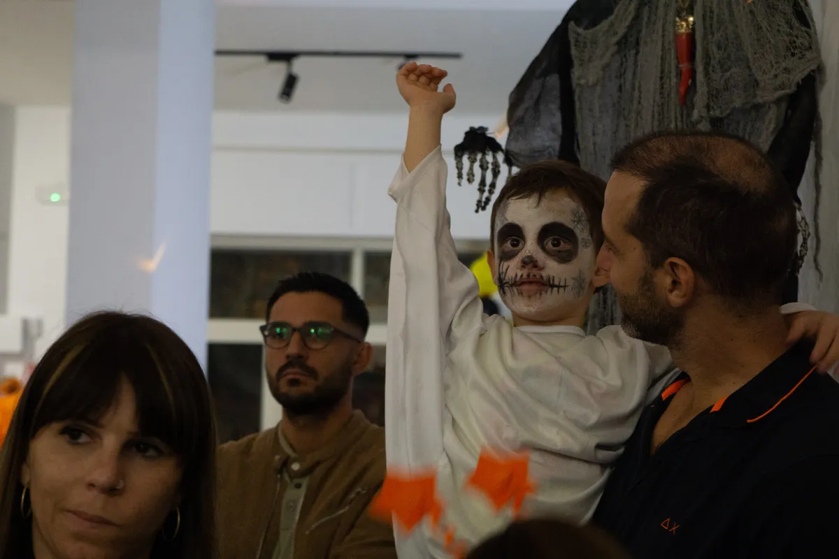 Bambino truccato da scheletro alza la mano per partecipare allo show